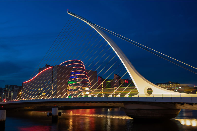 City skyline and bridge illuminated at night along a river – Energi IQ – Energy Assessment Services, energy assessment services ireland, energy assessment services uk, energy compliance experts, sustainable building solutions.